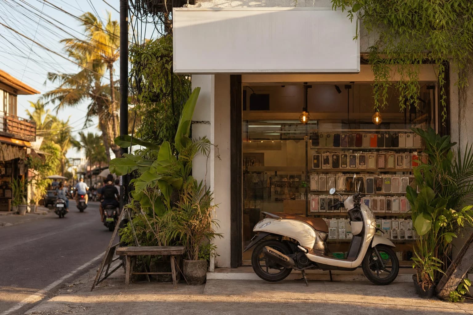 Shopfront of a small phone repair workshop on a busy Canggu street in the late afternoon, scooter parked in front of a window packed with cases and chargers, blank signboard, overflowing tropical greenery and the tangle of overhead power cables typical of Balinese streets